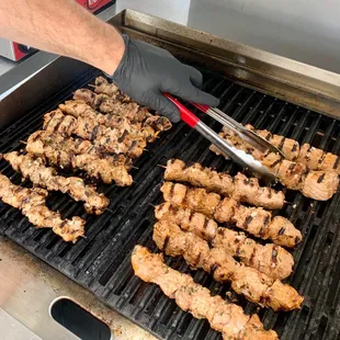 a person using tongs to cut meat on a grill