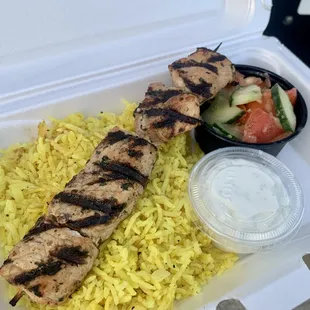 a chicken skewer with rice and vegetables