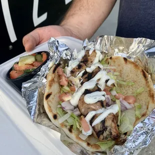 a person holding a taco in foil