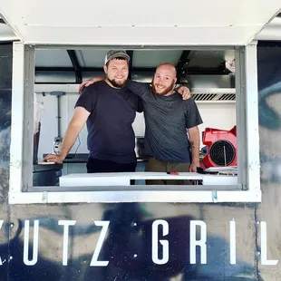 two men standing in a food truck