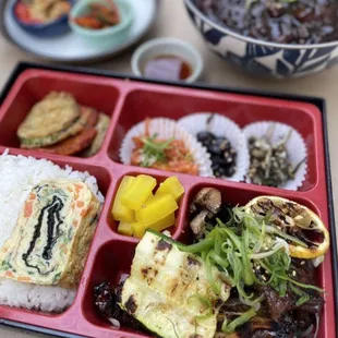 a bento box with rice, vegetables, and meat