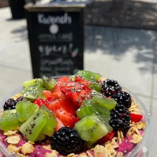 a hand holding a bowl of fruit