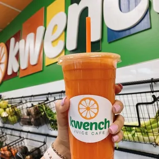 a hand holding a cup of juice