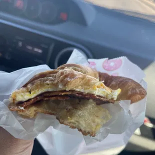a hand holding a breakfast sandwich