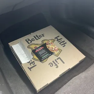 a box of pizza in the trunk of a car