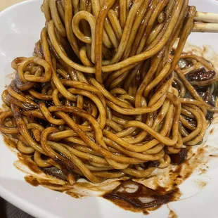 a plate of noodles with chopsticks