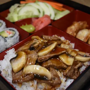 a bento box with rice, meat and vegetables