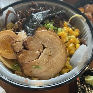 a bowl of ramen with a side of corn