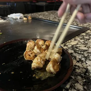 a person holding chopsticks over a plate of food