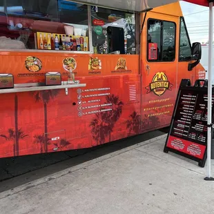 an orange food truck parked under a red awning