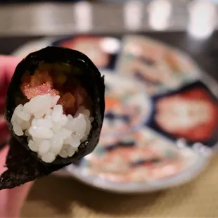 a hand holding a piece of sushi