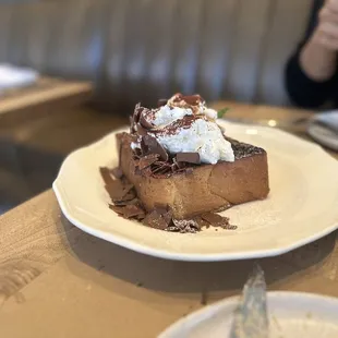 a plate of french toast with whipped cream and chocolate