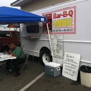 a man sitting at a table in front of a food truck
