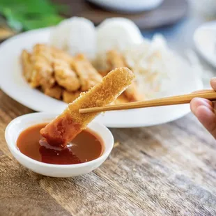 a person dipping sauce into a bowl