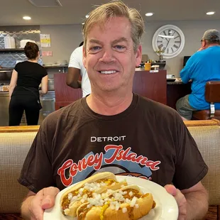 a man holding a plate of hot dogs