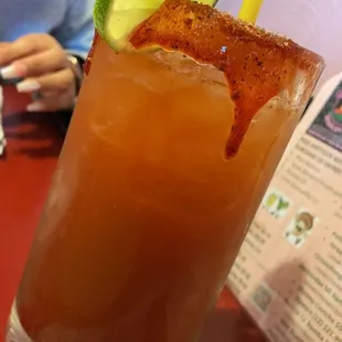 a tall glass of a drink with a cucumber garnish