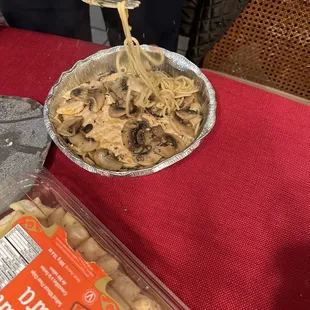 a bowl of noodles and a container of mushrooms