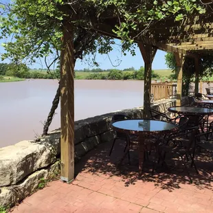 a patio with tables and chairs overlooking a river
