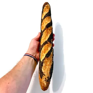 a hand holding a long loaf of bread