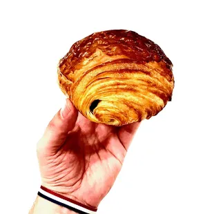 a hand holding a croissant