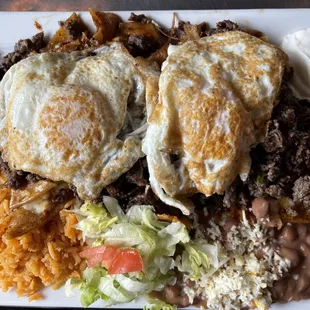 Chilaquiles = Fried strips of tortilla, sautéed with green [mild] or red [spicy]salsa &amp; topped with cheese, sour cream and onions. + Carne A