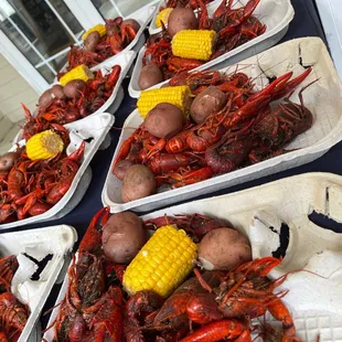 a table full of craws, potatoes, corn, and potatoes