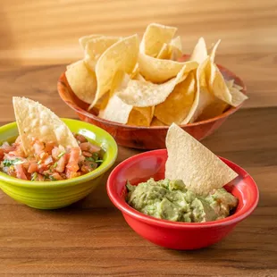 two bowls of guacamole and chips