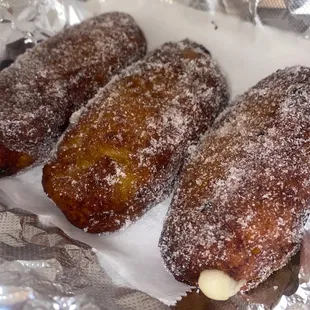 three doughnuts covered in powdered sugar