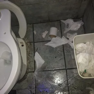 a toilet with toilet paper and a bucket of toilet paper