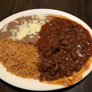 Chile Colorado meal that came with refried beans topped with cheese, Spanish rice and flour tortillas.