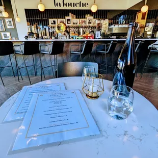 a table with a menu and a bottle of wine