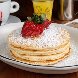 Homemade fluffy traditional pancakes topped with fresh strawberry.