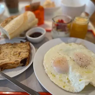 Petit dejeuner deluxe - eggs over medium, bread pudding, yogurt, baguette with butter and homemade jam, fresh squeezed juice, and coffee