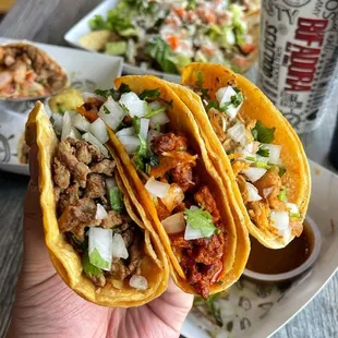 a hand holding two tacos