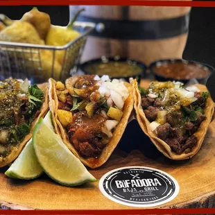 three tacos with lime wedges