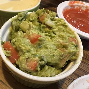 Medium guacamole . Cheese dip in the background