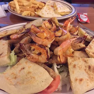 Plato Mixto mediano. Beef,Chicken &amp; shrimp over a salad. Pupusas included. Other plate is a kids quesadilla w/ french fries.