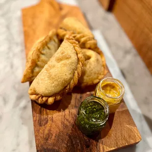 a plate of empanadas and a small bowl of salsa