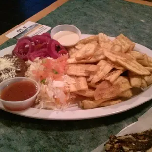 Side dishes for Honduran fish platter: (clockwise from left) bean puree, pickled onions, sauce 1, fried bananas, coleslaw, sauce 2