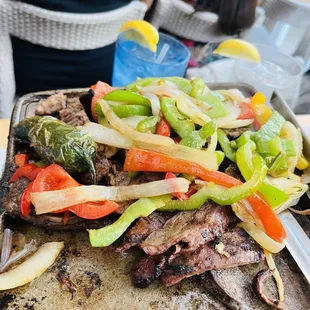Fajitas smoking hot lots of peppers and onions.