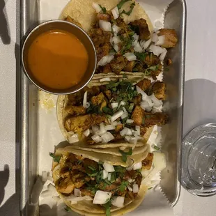 a tray of tacos and sauce