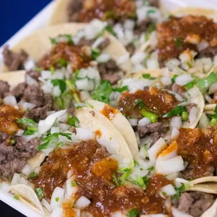 a tray of tacos with meat and onions