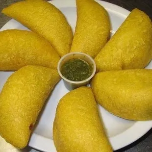 a white plate with a small bowl of green sauce