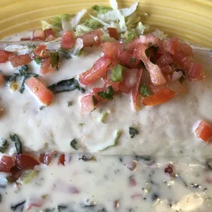 Burrito supreme - ground beef, shredded pork, rice and beans in a flour tortilla covered with spinach queso and pico