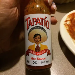 a hand holding a bottle of tapatio