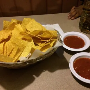 a bowl of chips and two bowls of salsa