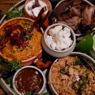 Michoacan family style meal; chicken tinga, pork carnitas, rice, refried beans, crema, and salsas.
