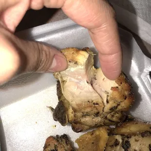 a person picking up a piece of chicken