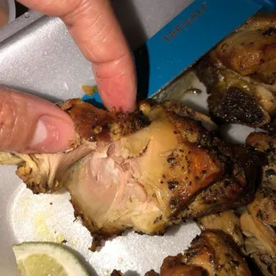 a person picking up a piece of chicken