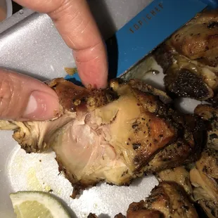 a person picking up a piece of chicken